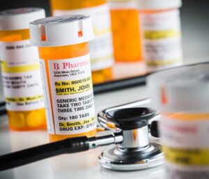 Prescription medicine bottles with labels and a stethoscope on a table.