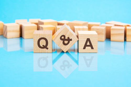 Wooden blocks with letters Q and A against a blue background, reflecting on a shiny surface.